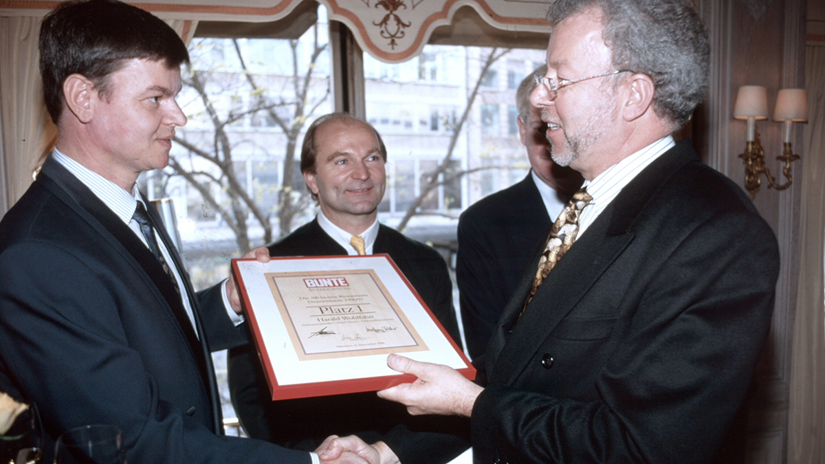 1996 im Königshof: BUNTE Restaurant-Experte Wolfgang Ritter überreicht die Urkunde an Harald Wohlfahrt. Promi-Wirt Sepp Krätz darf dabei nicht fehlen.